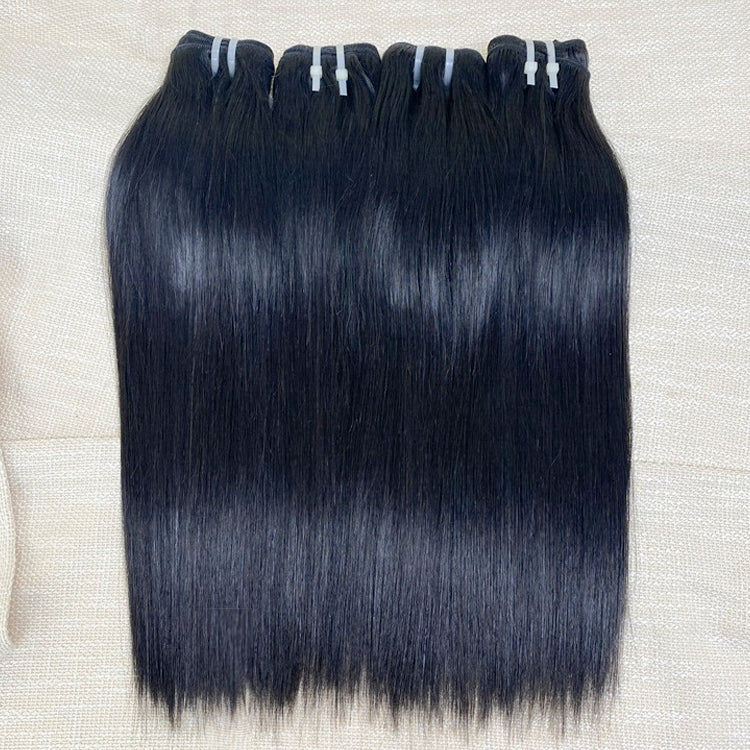 Three bundles of straight black human hair extensions laid out on a surface.
